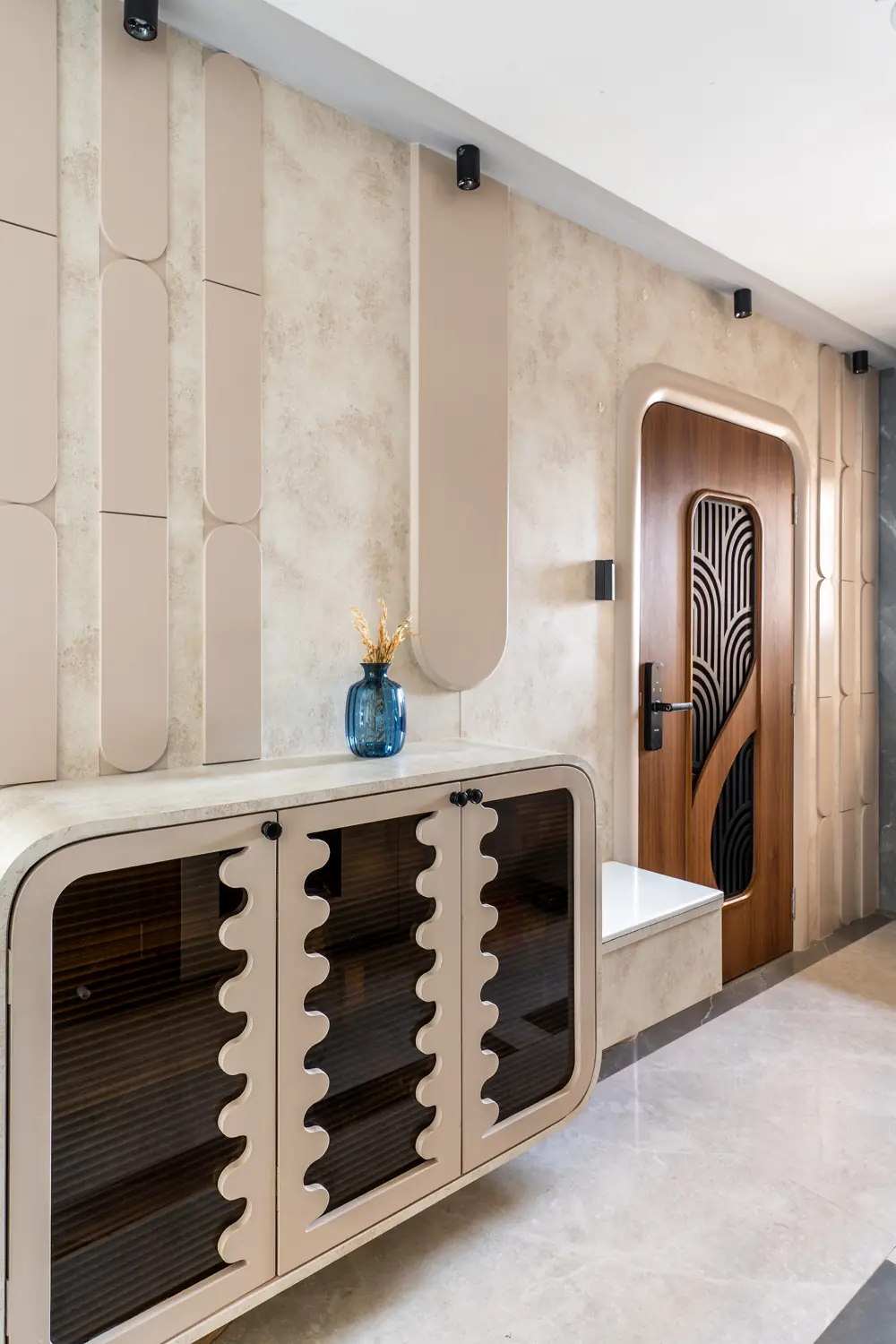 Curved cream console with scalloped smoked-glass doors at the entrance